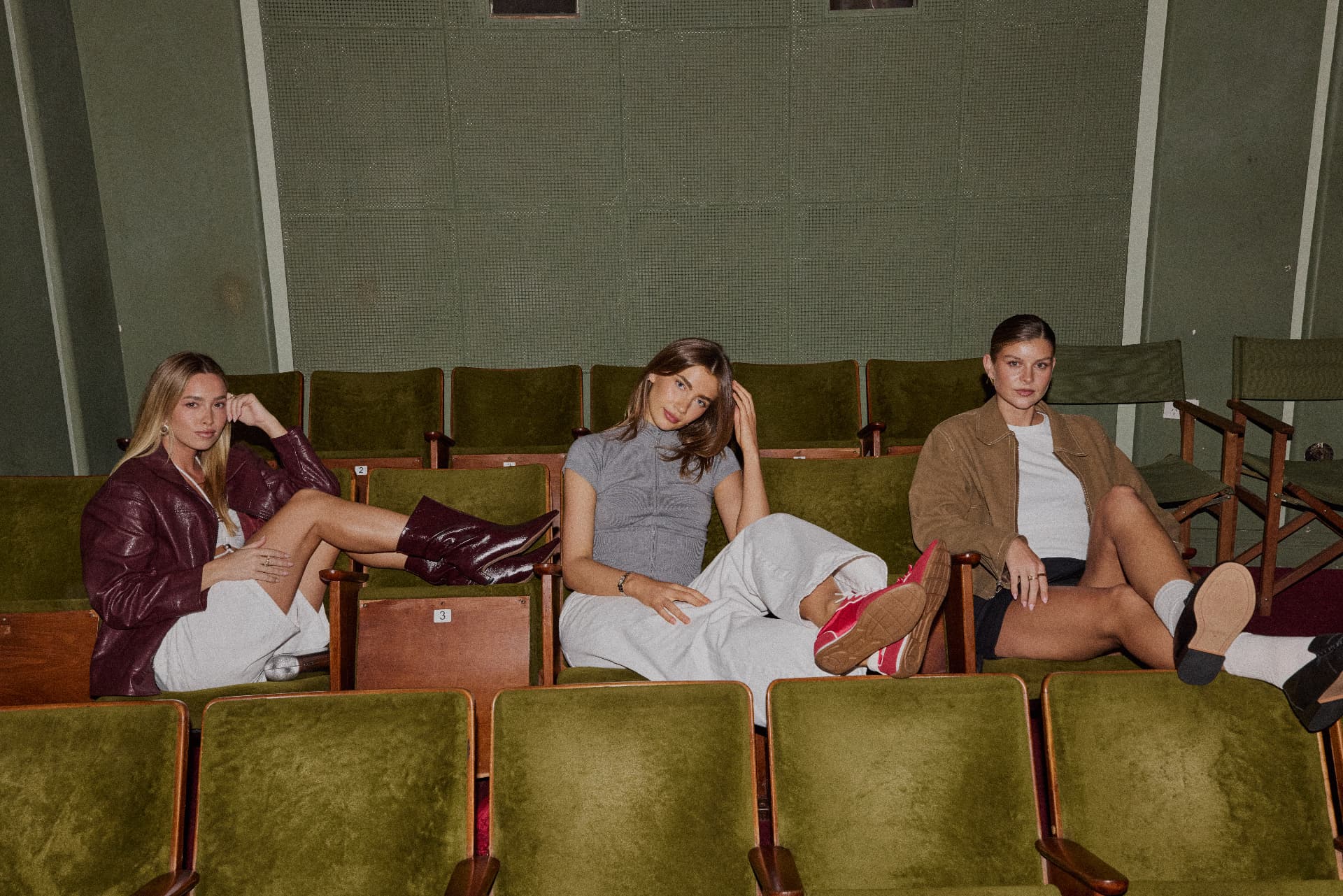 Three fashion creators lounging across the retro cinema seats